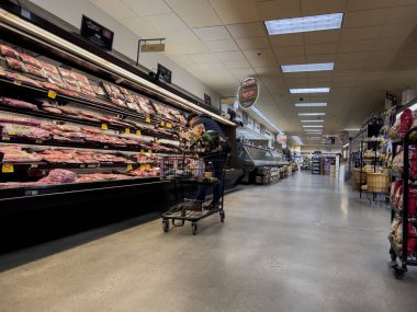 Woodinville, WA USA - Aralık 2022: Haggen 'de bir markette soğutulmuş et reyonundan alışveriş yapan yaşlı bir adamın geniş görünümü.