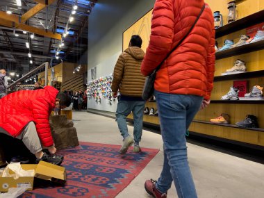 Bellevue, WA USA - Aralık 2022: Bir REI mağazasının içinde yürüyüş botları ve diğer açık hava ayakkabıları için alışveriş yapan insanların geniş görünümü.