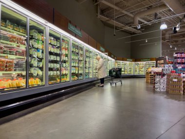 Mill Creek, WA USA - circa December 2022: Wide view of a woman shopping in the refrigerated section of a Town and Country Market.