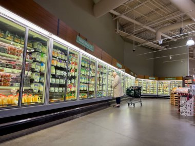 Mill Creek, WA USA - circa December 2022: Wide view of a woman shopping in the refrigerated section of a Town and Country Market.