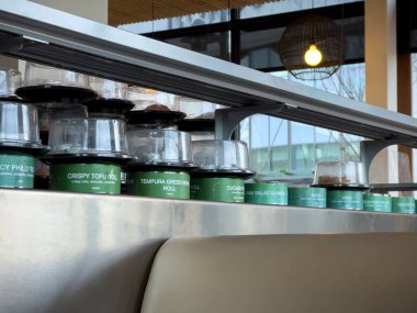 Lynnwood, WA USA - circa January 2023: Selective focus on fresh sushi on a conveyor belt inside Bitty Fish Japanese restaurant at the Alderwood Mall.