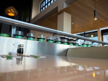 Lynnwood, WA USA - circa January 2023: Selective focus on fresh sushi on a conveyor belt inside Bitty Fish Japanese restaurant at the Alderwood Mall.