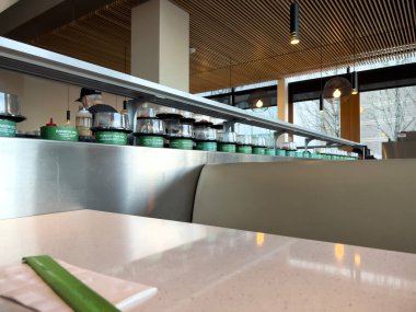 Lynnwood, WA USA - circa January 2023: Selective focus on fresh sushi on a conveyor belt inside Bitty Fish Japanese restaurant at the Alderwood Mall.