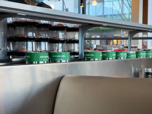 Lynnwood, WA USA - circa January 2023: Selective focus on fresh sushi on a conveyor belt inside Bitty Fish Japanese restaurant at the Alderwood Mall.