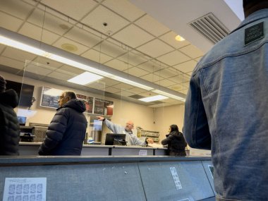 Mill Creek, WA USA - circa December 2022: Wide view of people dropping off and picking up packages inside a USPS office