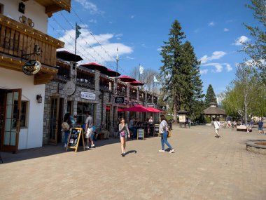 Leavenworth, WA USA - Nisan 2023: Şehir merkezindeki alışveriş bölgesinde güneşli havanın tadını çıkaran insanlar ve köpekler