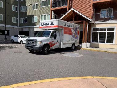Lynnwood, WA USA - Ağustos 2023: Parlak güneşli bir günde yüksek katlı bir apartmanın önünde park etmiş bir U nakliye kamyonunun geniş görüşü