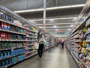 Everett, WA USA - Temmuz 2023: Maskeli bir kadının WinCo marketinin hijyen bölümünde alışveriş yapması.