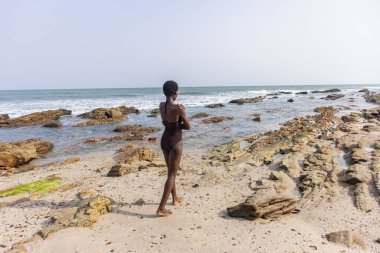 Sahilde mayo giymiş Afrikalı bir kadın.