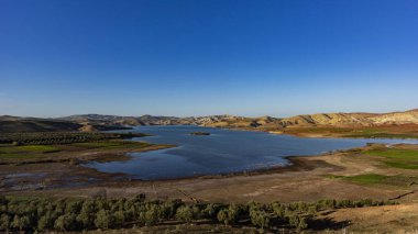 Fas 'ta kuru tepeler ve yeşil tarlalarla çevrili bir göl.