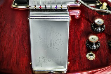 Closeup of guitar tone and volume witch hat knobs with lyre maestro vibrato tremolo tail piece on red 1966 Gibson SG solid guitar standard, electric musical instrument. old school retro clipart