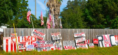 OCALA, FLORIDA USA - OCTOBER 22, 2023 Pro president trump signs anti Biden, republican vs democratic political party picket on fence with American flags in rural north Florida , election 2024 clipart