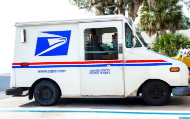Ocala, Florida, USA November 2, 2023 USPS truck delivering mail on suburban street parked in occupied space. red white and blue concept colors with American Bald eagle mascot logo emblem clipart