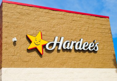 OCALA, FLORIDA ABD - 14 Ekim 2023 Hardees beyaz bulutlar ile mavi gökyüzü arka plan imzalar. Sarı yıldız, gülümseyen yüz logosuyla kırmızı süslemeli, beyaz harfli kahverengi tuğlalı dış tabelalı.