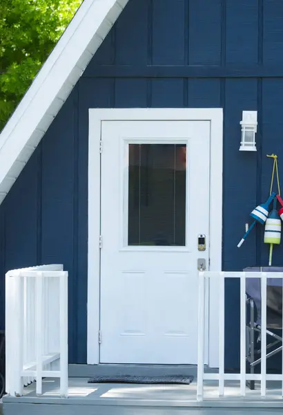 可爱可爱的近景三角形的房子或带有深蓝色门 木制前廊栏杆 航海主题装饰的家 免版税图库照片