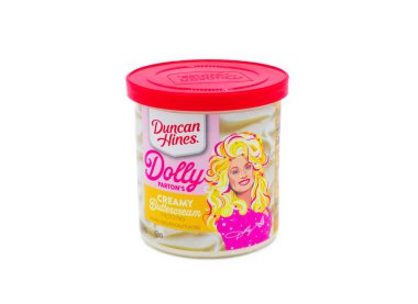 Öcala, FL 3-31-2024 Dolly Parton kremalı krema. Yazan Duncan Hines, doğal ve yapay aromalı. Beyaz arkaplanda parlak kırmızı kapaklı konteynır üzerindeki pembe ve sarı renkler