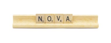 Yeni doğmuş popüler bebek adı NOVA. Kare ahşap kaplama İngiliz alfabesi harfleri ve beyaz arka planda izole edilmiş ahşap tutacağında tahıl var.