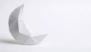 Zamanın ritmini ve en derin duygularımızı ve içgüdülerimizi temsil eden Ay 'ın beyaz arka planında fotokopi alanı ile izole edilmiş kağıt origami ay ışığı kavramı, çocuklar için basit başlangıç sanatı.