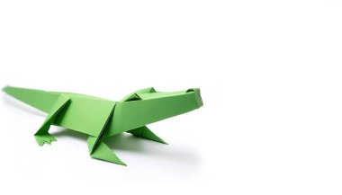 Hayvan konsepti origamisi, beyaz arka planda izole edilmiş yeşil Amerikan timsahı - timsah misssippiensis - fotokopi alanı yan görüşlü, çocuklar için basit marş teknesi