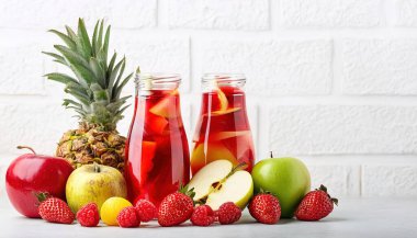 Bir sürahide elma, portakal, ananas, çilek, üzüm ve yaban mersini karışımı. Mükemmel bir yaz zamanı alkollü içki. beyaz arkaplanda izole
