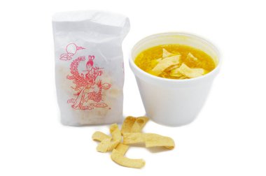 Egg drop or egg flower soup is a Chinese soup of wispy beaten eggs in chicken broth often served in American chinese take out restaurants.  served in styrofoam cup with a bag of crispy fried noodles clipart