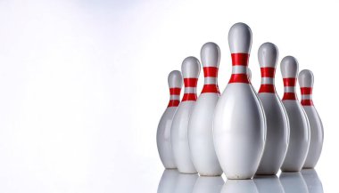 Minimalist photo of white bowling pins with two red horizontal stripes on neck of pin. set up for ten pin game. isolated on white background with copy space clipart