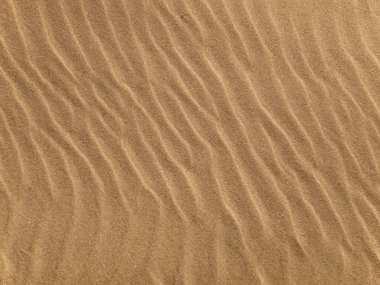 Arka plan olarak kumlu bir sahilde dalga deseni