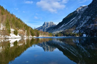 İtalya 'nın Friuli-Venezia Giulia bölgesinde Tarvisio yakınlarındaki Lago del Predil manzarası Cinque Punte dağlarının zirveleri ve sudaki dağların yansıması.
