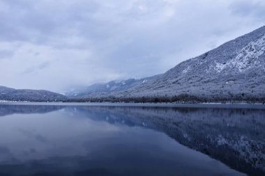Julian Alpleri, Gorenjska, Slovenya 'da kışın yükselen orman kaplı dağlarla Bohinj Gölü manzarası
