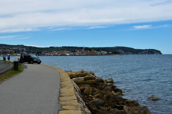 Izola, Slovenya - 16 Nisan 2023: Adriyatik Denizi kıyısında Izola ve Strunjan yarımadası kıyılarında siyah bir minibüs ve Istrian maratonunda bir çift koşucu