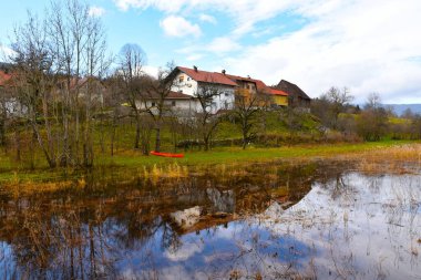 Laze pri Gorenjem Jezeru köyü ve Slovenya 'nın Notranjska kentindeki Cerknisko Jezero gölündeki binaların yansıması.