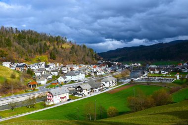 Slovenya 'nın Gorenjska kentindeki Gorenjska vas köyünün manzarası gökyüzündeki güneş ışığı bulutlarıyla aydınlanıyor