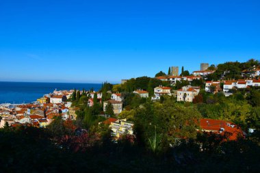 Slovenya 'nın Adriyatik Denizi kıyısındaki Istria ve Littoral bölgesindeki eski Piran kasabasının üzerindeki evler ve ortaçağ savunma kuleleri ve Piran duvarı
