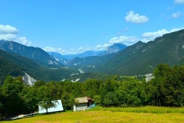 Resia Alp Vadisi 'nin panoramik manzarası. Önünde bir çayır ve İtalya' nın Friuli Giulia bölgesinde bir orman var.
