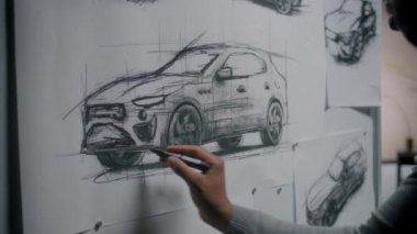 Otomotiv Afrikalı Amerikalı erkek tasarımcı beyaz tahtada işaretli taslak çiziyor, yeni nesil elektrikli araba tasarımı geliştiriyor. Modern araba tasarım stüdyosunda çalışıyor..