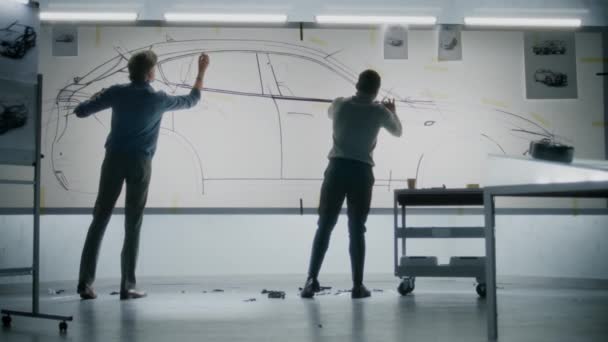 2人の多様な自動車男性デザイナーがホワイトボードにマーカーでスケッチを描き 未来の電気自動車の未来のデザインを開発しました 彼らは現代の車の設計開発スタジオで働いています — ストック動画