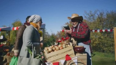 Çift yerel çiftçi pazarından meyve ve sebze alır. Temas kurulamayan bir kadın akıllı telefon kullanarak satın almaya para ödüyor. Hafta sonları açık havada sonbahar festivali. Vejetaryen ve organik yiyecekler. Tarım.