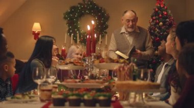 Drandfather aile Noel yemeğinde İncil okur. Noel 'i ya da 2023 yılını kutlamadan önce dua eden çok sayıda aile var. Lezzetli yemek ve mumlarla servis edilen tatil masası. Kış tatili.