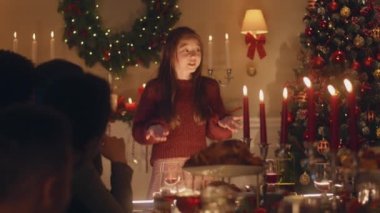 Genç Asyalı kız fıkra anlatır, şiir anlatır ya da çok kültürlü bir aileyle oyun oynar. Noel 'i kutluyorlar. Tabaklar ve mumlarla servis edildi. Aile içinde sıcak bir Noel yemeği..