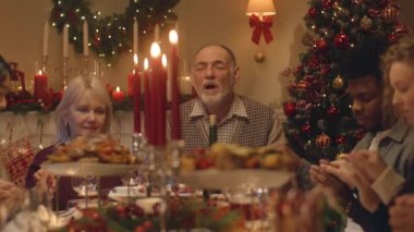 Noel 'den önce dua eden mutlu büyük aile, sonra yemek yemeye ve kutlamaya başlar. Lezzetli yemek ve mumlarla servis edilen tatil masası. Aile yemeği için sıcak bir ortam..