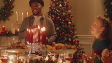 Mutlu çok kültürlü aileler Noel 'i ya da 2023 yılını kutluyor, hediyelerimizi değiş tokuş ediyoruz. Farklı yemek ve mumlarla servis edilen tatil masası. Aile içinde sıcak bir Noel yemeği..