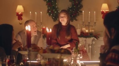 Genç Asyalı kız fıkra anlatır, şiir anlatır ya da çok kültürlü bir aileyle oyun oynar. Noel 'i kutluyorlar. Tabaklar ve mumlarla servis edildi. Aile içinde sıcak bir Noel yemeği..