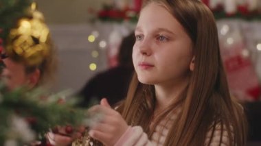Genç kız Noel ağacını toplar ve oyuncaklarla süslüyor. Noel 'den ya da yeni yıldan önce aile evi hazırlığı. Kış tatilinde evin rahat atmosferi. Yakın çekim görüntüsü. Yavaş çekim.