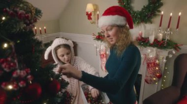 Anne ile kızı topları ve oyuncakları seçiyor, Noel ağacını süslüyor. Pijamalı genç kız şeker yalıyor ve Noel tatilinden önce evi hazırlamak için anneye yardım ediyor. Sıcak bir evde kışın büyüsü.