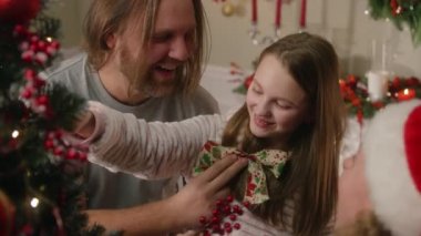 Kafkasyalı mutlu bir aile eğleniyor ve gülüyor. Noel ağacını Noel ya da yeni yıl için evde toplar ve dallarla süslüyorlar. Kış tatili için şölen süsleri..