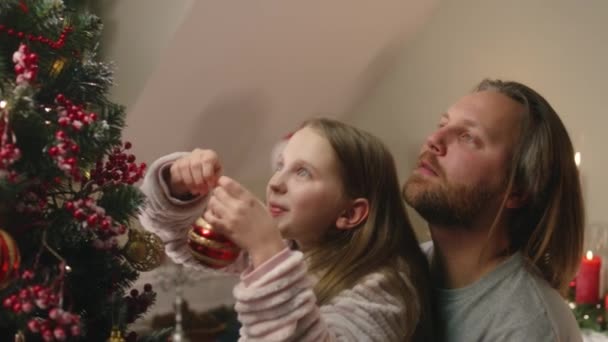 Padre Levanta Pequeña Hija Para Poner Bola Navidad Árbol Feliz — Vídeo de stock