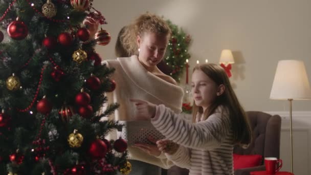 Gelukkig Jong Meisje Met Moeder Versieren Kerstboom Met Ballen Speelgoed — Stockvideo