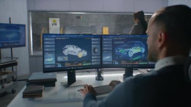 Deneysel kaza testi laboratuvarında çalışan kadın ve erkek mühendisler, bilgisayar sistemi kullanan elektro çevre dostu yeni bir arabanın güvenlik parametrelerini almak için trafik kazası simülasyonu sürecini izliyorlar..