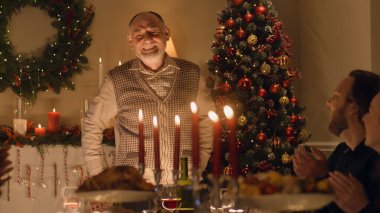 Kıdemli adam büyük çok kültürlü ailesine fıkra ya da hayat hikayesi anlatır. Noel 'i kutluyorlar. Tabaklar ve mumlarla servis edildi. Aile içinde sıcak bir Noel yemeği..