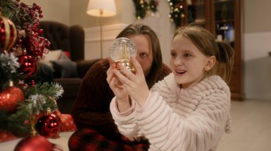 Noel 'de dekore edilmiş Noel ağacının altında mutlu Kafkas ailesi hediyeleri açıyor. Genç kız sihirli kar kürelerini açıyor. Noel 'de ya da yeni yılda evde sıcak bir atmosfer olur. Kış tatili.